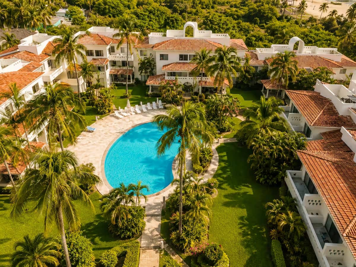 Vista desde el aire de un condominio con alberca, jardines y palmeras en Manzanillo